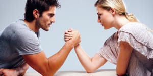 Young couple arm wrestling against grey background